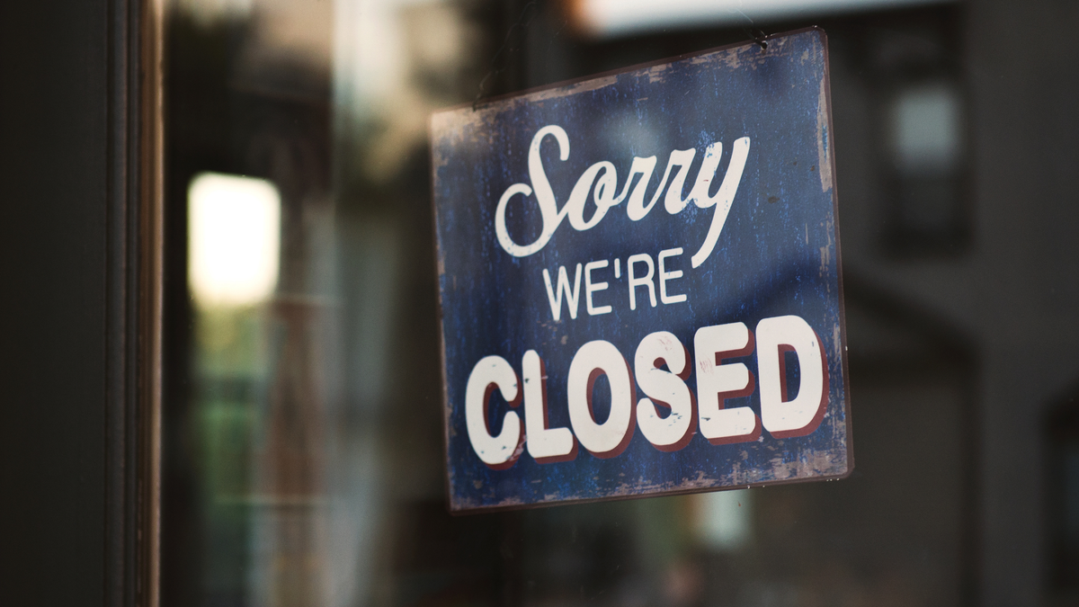 Picture of a store front with a sign that says "Sorry we're closed" in the window