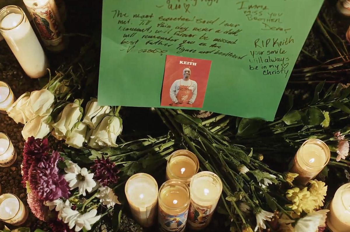 Candles and flowers next to a memorial.