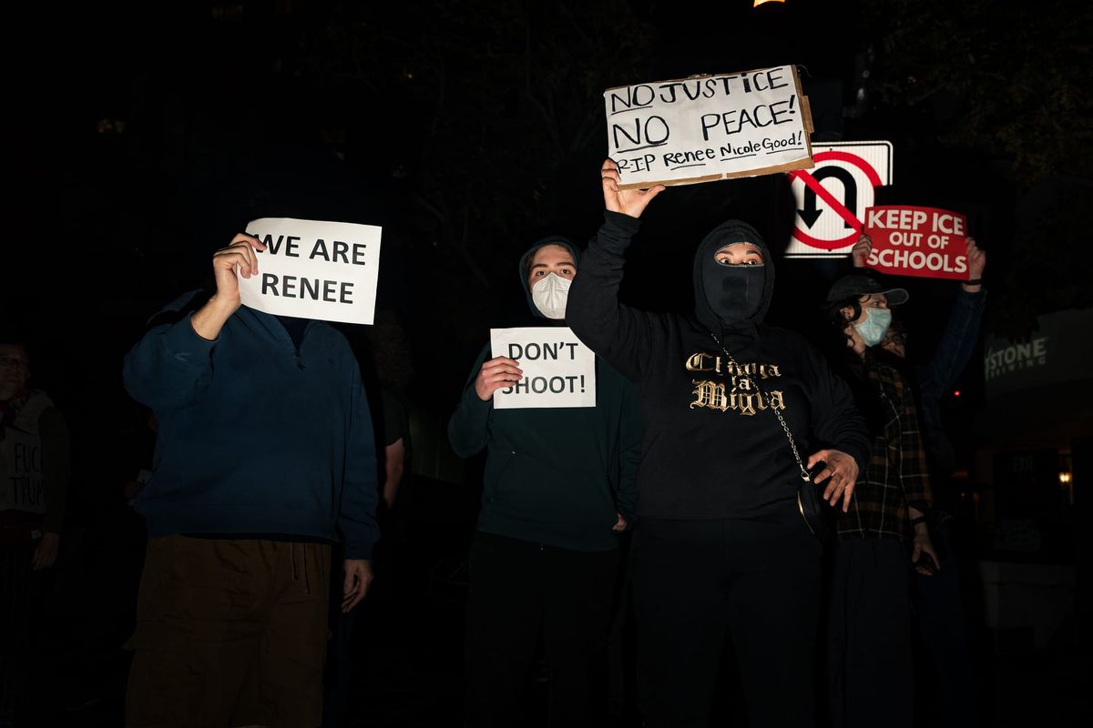 Four people wearing black hold up signs supporting Renee Nicole Good and criticizing ICE