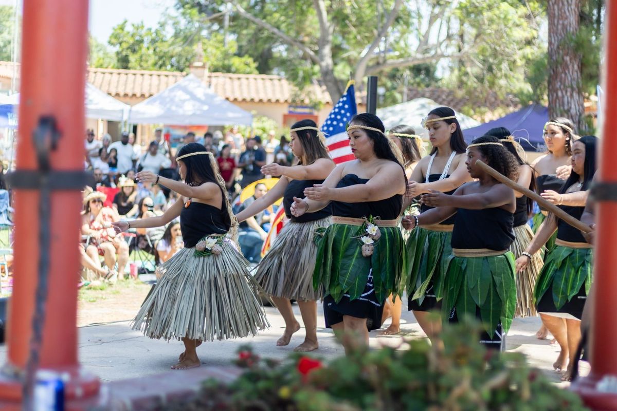 Dancers perform in front of an audience outside.