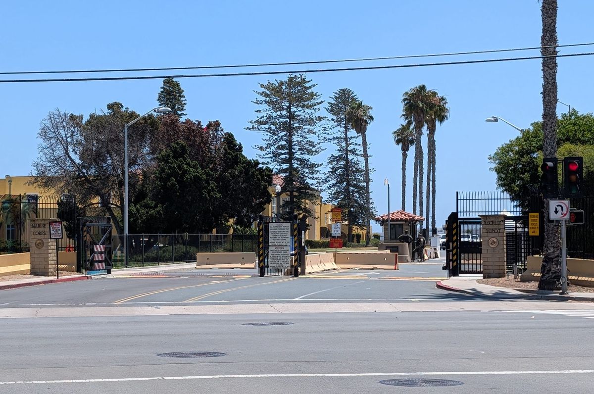 A gate with military guards and palm trees in the background