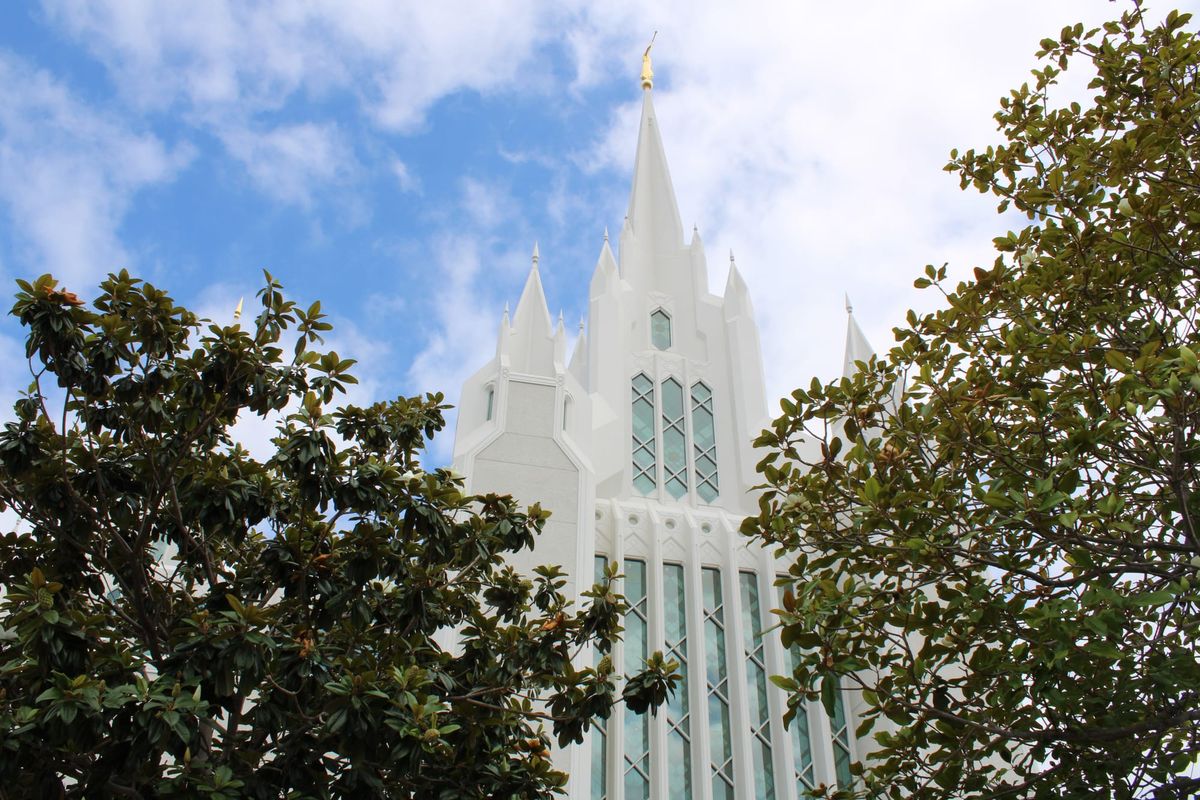 A white temple with tall spires with a cloudy sky in the background 