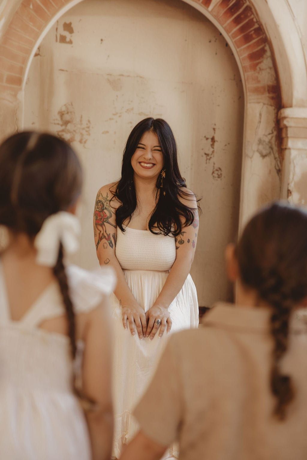 Picture of a woman in a white dress with two kids in front of her with their backs to the camera