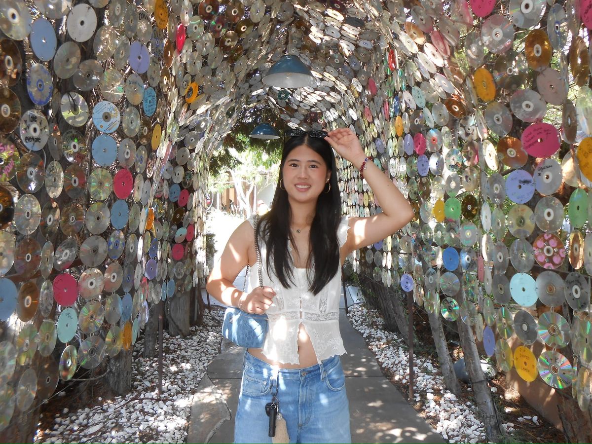 Emma Chen smiles while standing inside a tunnel covered with colorful CDs at The LAB Anti-Mall in Costa Mesa.