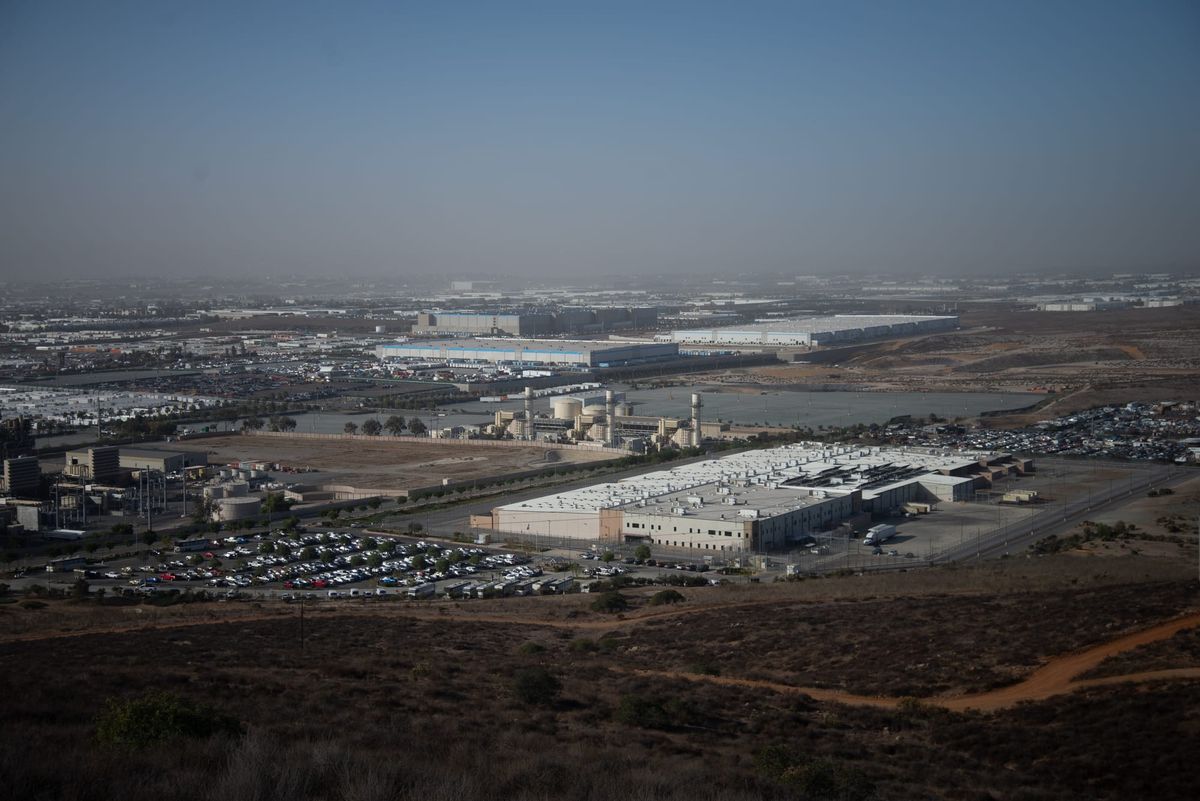 A prison building sits at the bottom of a hill next to an Amazon warehouse