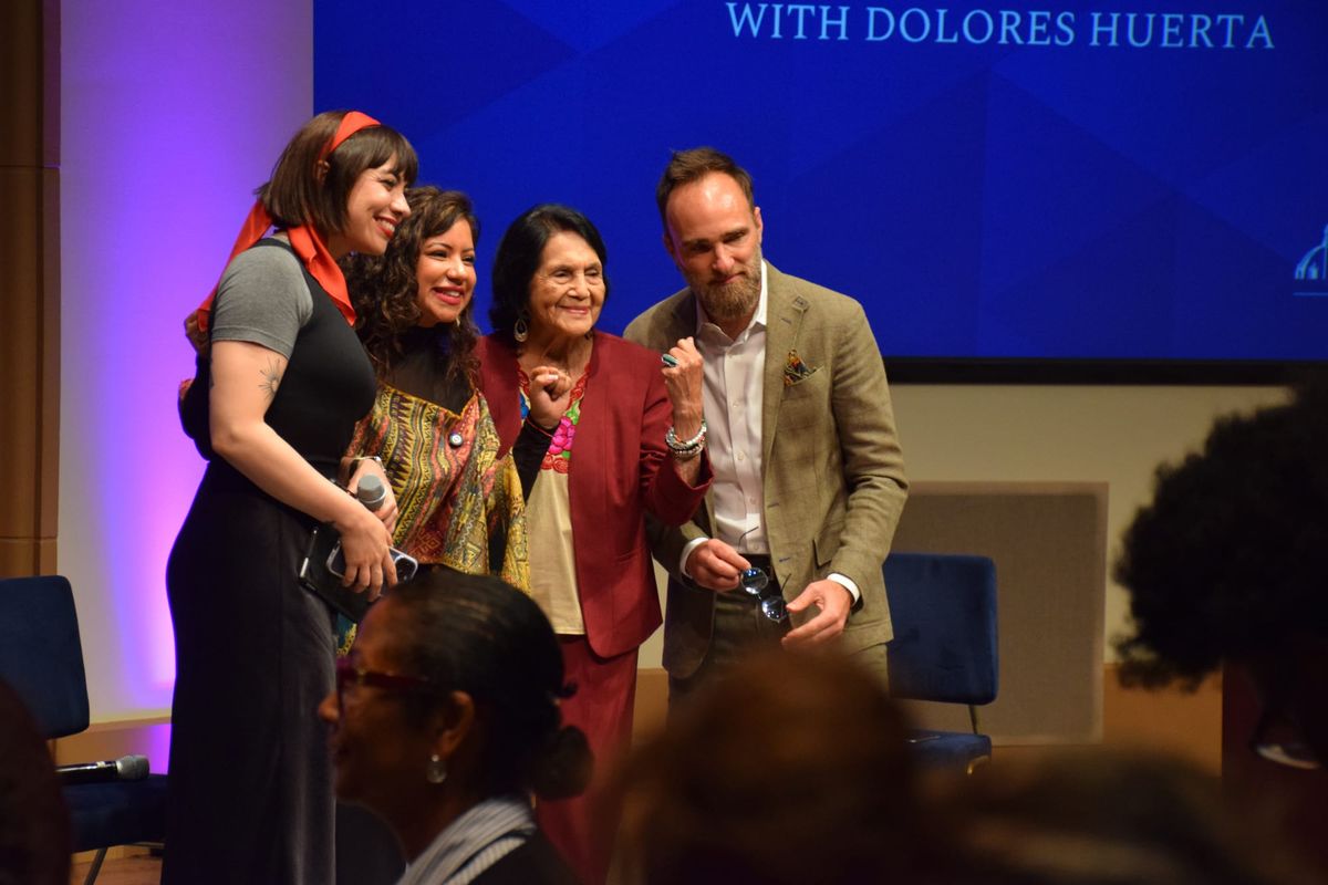 Four people stand on a stage next to each other while posing for a picture