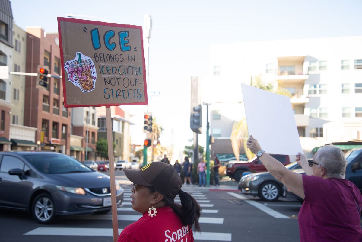 A person holds a sign that says ICE belongs in iced coffee not in our streets