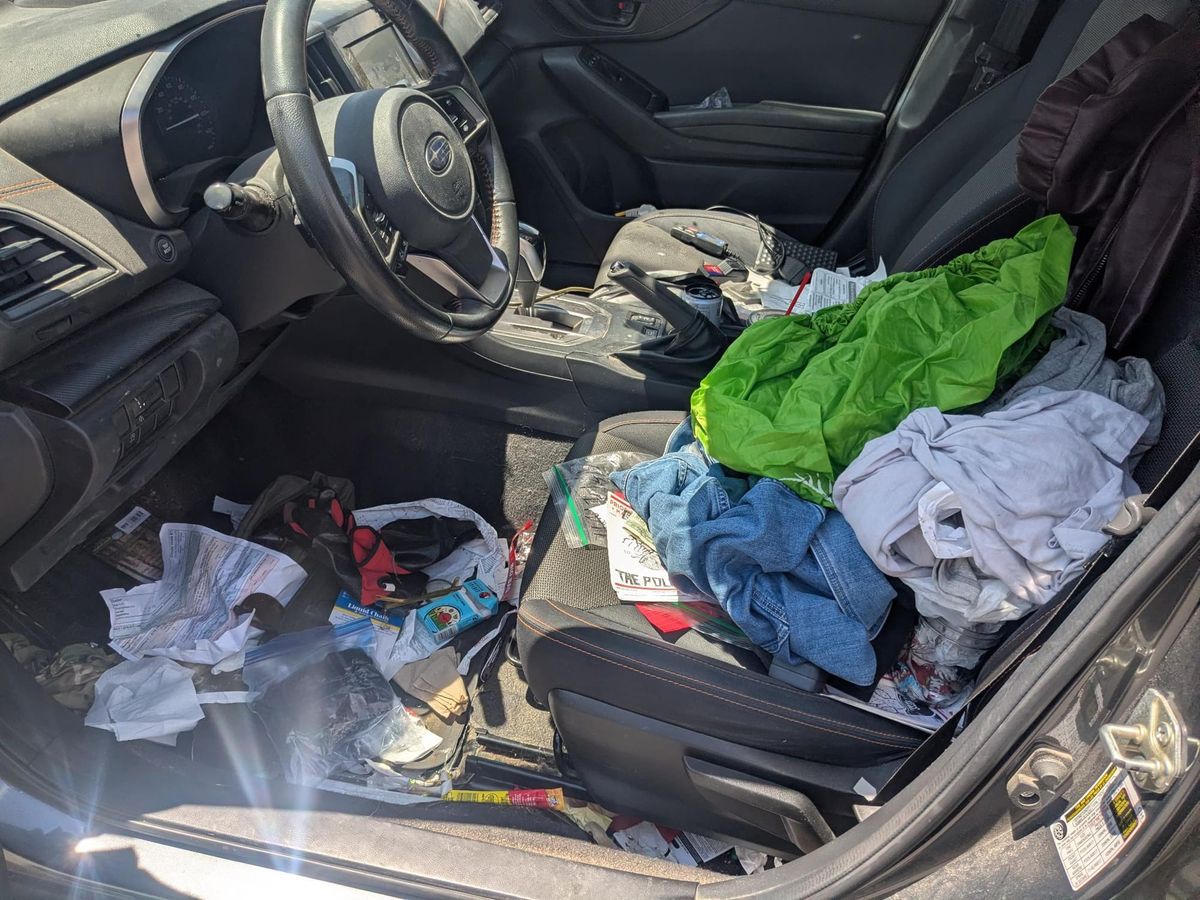 A car with papers, clothing and other materials all over the seats and floor.