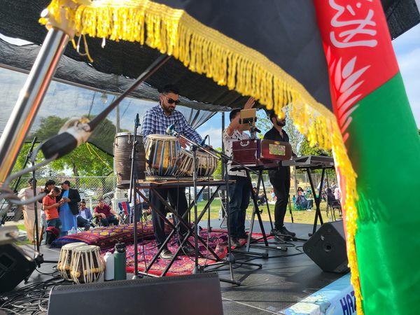 An Afghan flag frames a man playing a set of tabla drums