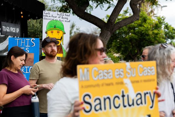 People protest outside holding signs with sayings like "Mi Casa es Su Casa Sanctuary" 