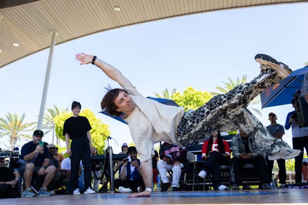 A dancer performs in a breaking competition outside in a park.