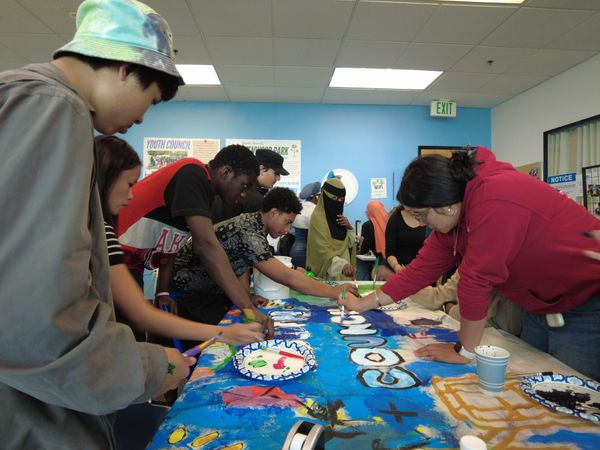 Side view of people leaning and reaching over, around table
