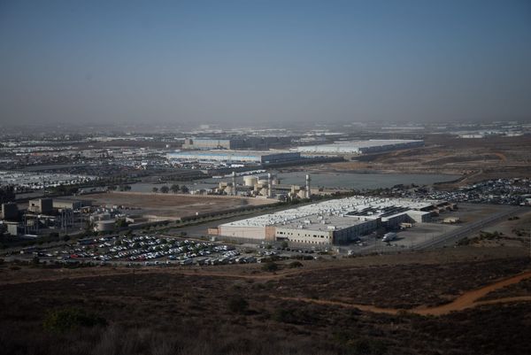 A prison-like facility lies at the bottom of a hill next to an Amazon warehouse
