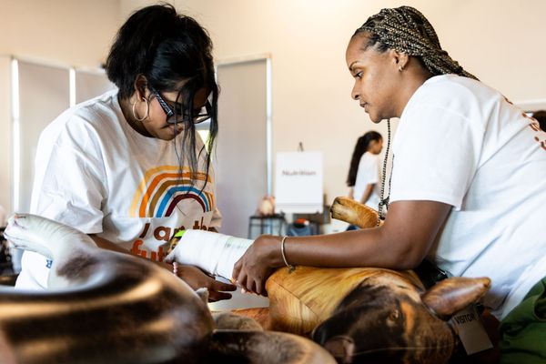 two people wrap a bandage on a fake dog in a workshop 
