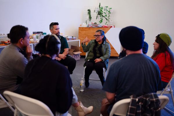 A woman speaks to a group of people sitting in chairs facing one another. 