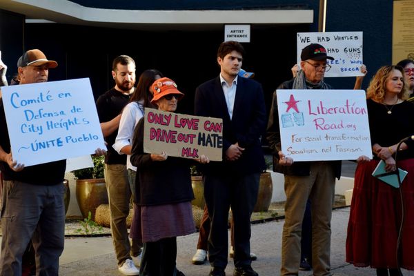 Several people hold homemade signs promoting community love and unity to protect neighbors from ICE