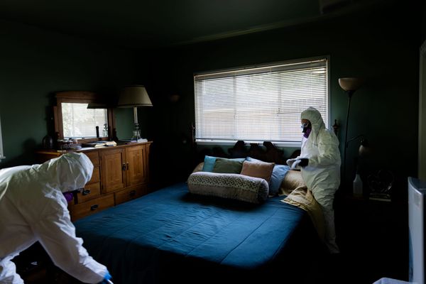 Picture of two people in personal protective equipment cleaning a bedroom