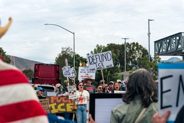 People in sunglasses and hats hold signs critical of ICE
