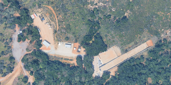 An overhead view of dirt rectangles shaped in a gun range and parking lot surrounded by trees