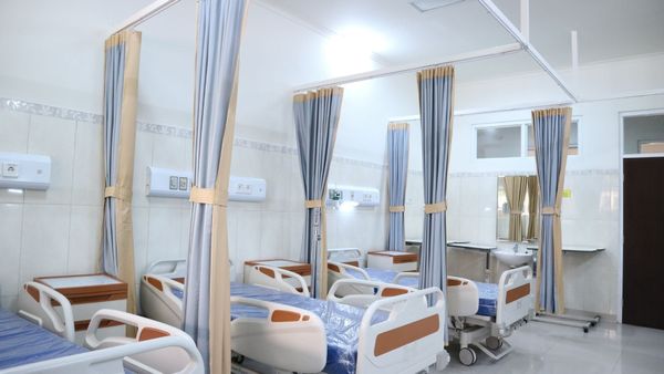 A row of hospital beds with blue curtains