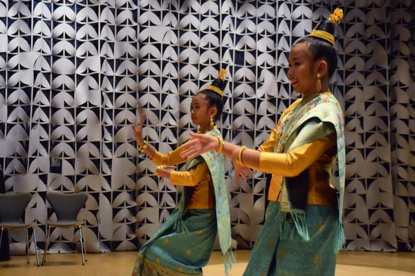 Two dancers perform in front of a patterned backdrop 