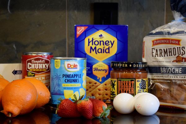 A picture of fruit, eggs, canned goods, a bag of bread, a jar of salsa and two boxes of cookies. 