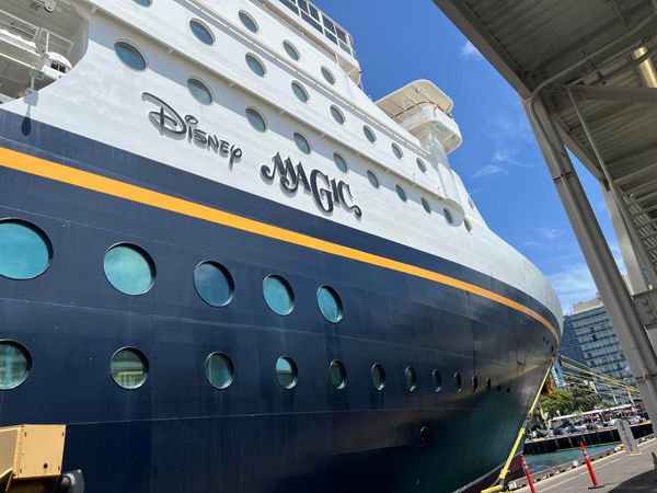 A blue white and yellow cruise ship with the Disney logo on the side and the name Magic