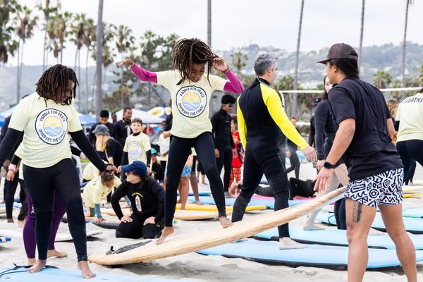 Kids practice surfing on the beach during a lesson