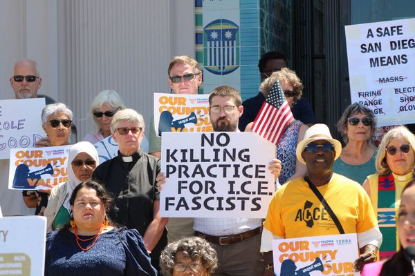 A man in glasses holds a sign that says No Killing Practice for ICE Fascists