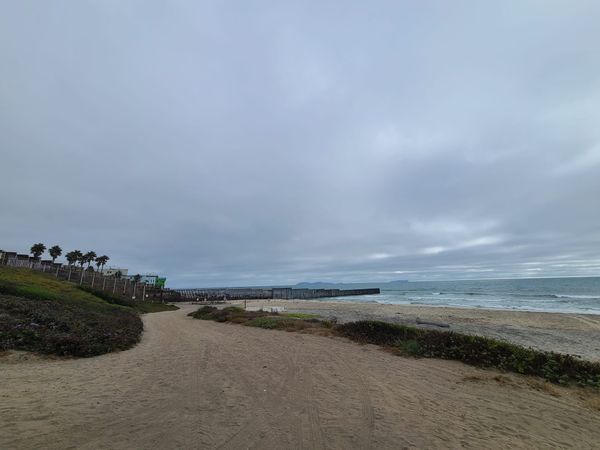 A beach with a rusted bollard-style wall at the far end