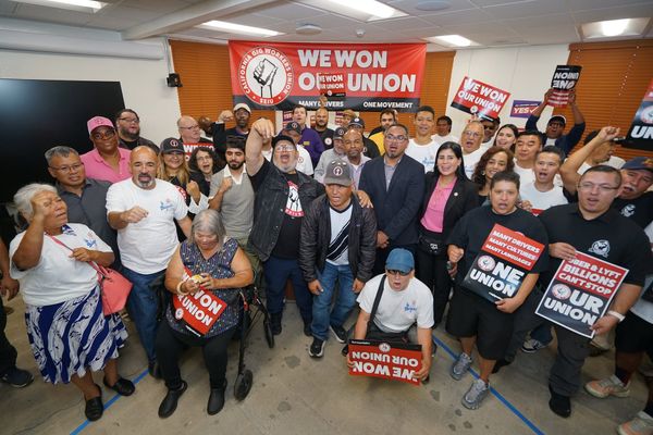 A group of people pose for a photo holding signs that read "We won our union" and "Uber & Lyft billions can't stop our union."