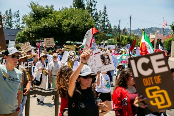 people with signs calling for ice out of san diego as well as mexican flags march in the street