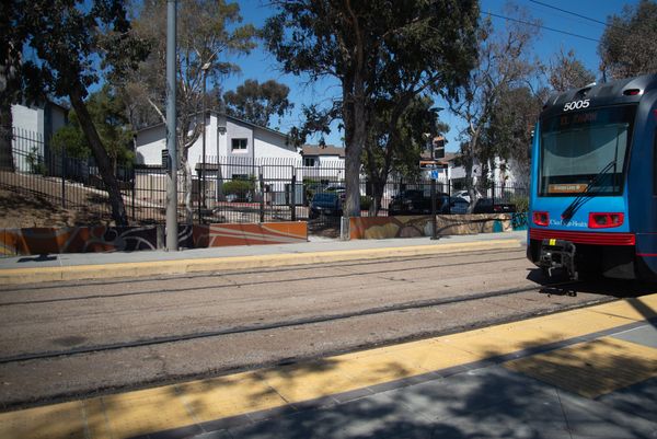 Picture of a trolley station with trees and houses in the background