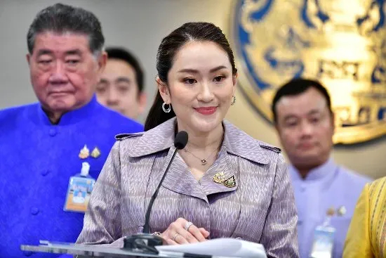 La Première Ministre thaïlandaise, debout derrière un micro, lors d'une conférence de presse.