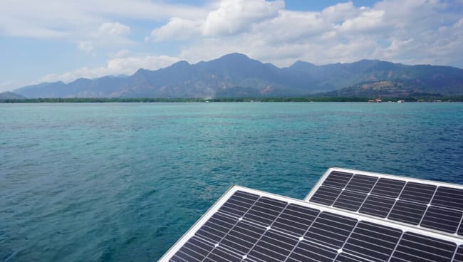 Panneaux solaires flottants, avec une chaîne de montagnes en fond.