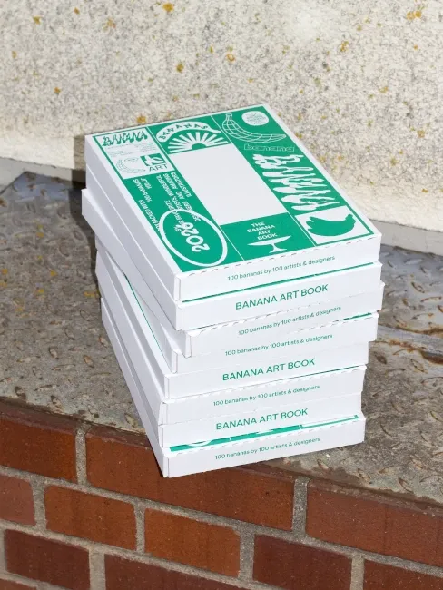 Le livre emballé dans son colis, ressemblant à un carton blanc recouvert de diverses inscriptions et pictos de couleur verte
