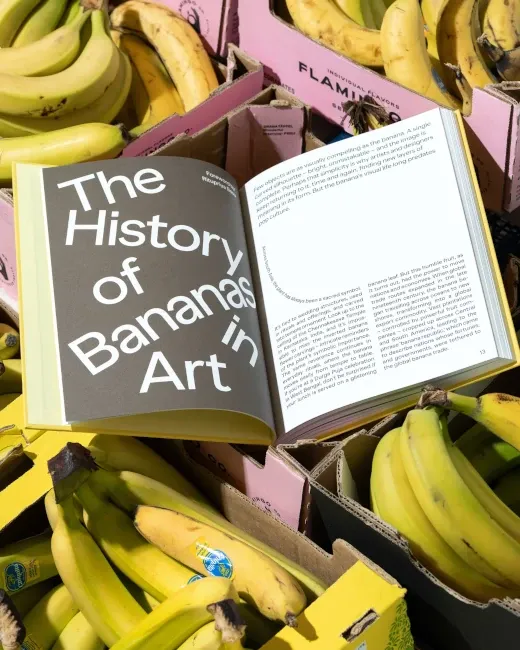 Le livre, posé sur un tas de bananes, ouvert à une page de texte dont le titre indique : "History of Bananas in art"
