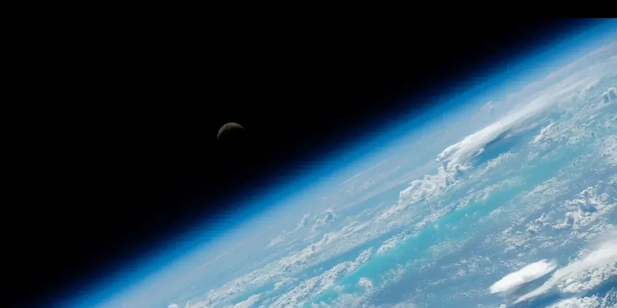 Vue depuis la Station Spatiale Internationale, la Terre est en gros plan et la lune se devine dans le lointain.