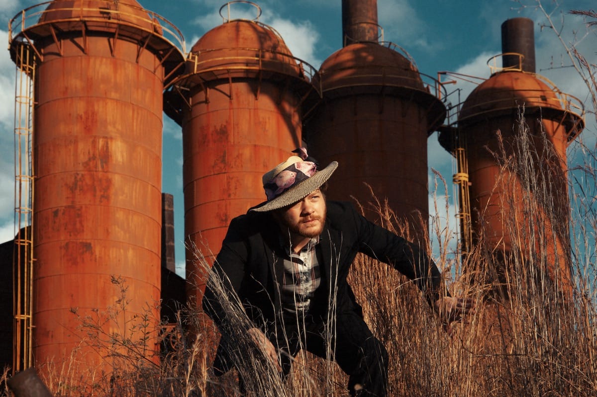 Early James portrait in front of four rust stained silos
