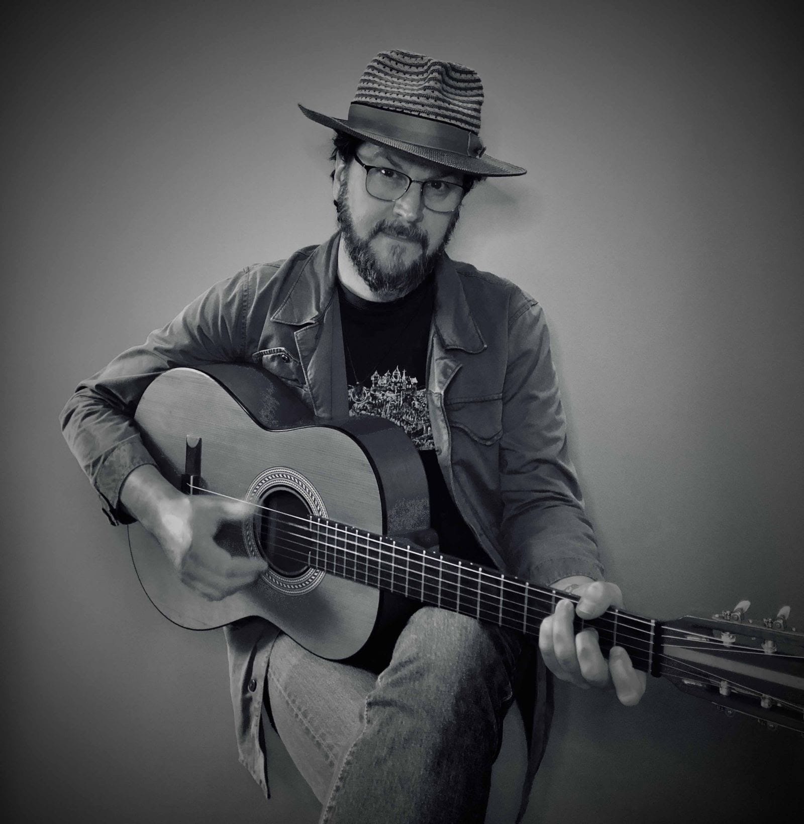 A black and white portrait of singer Kenny Roby with acoustic guitar
