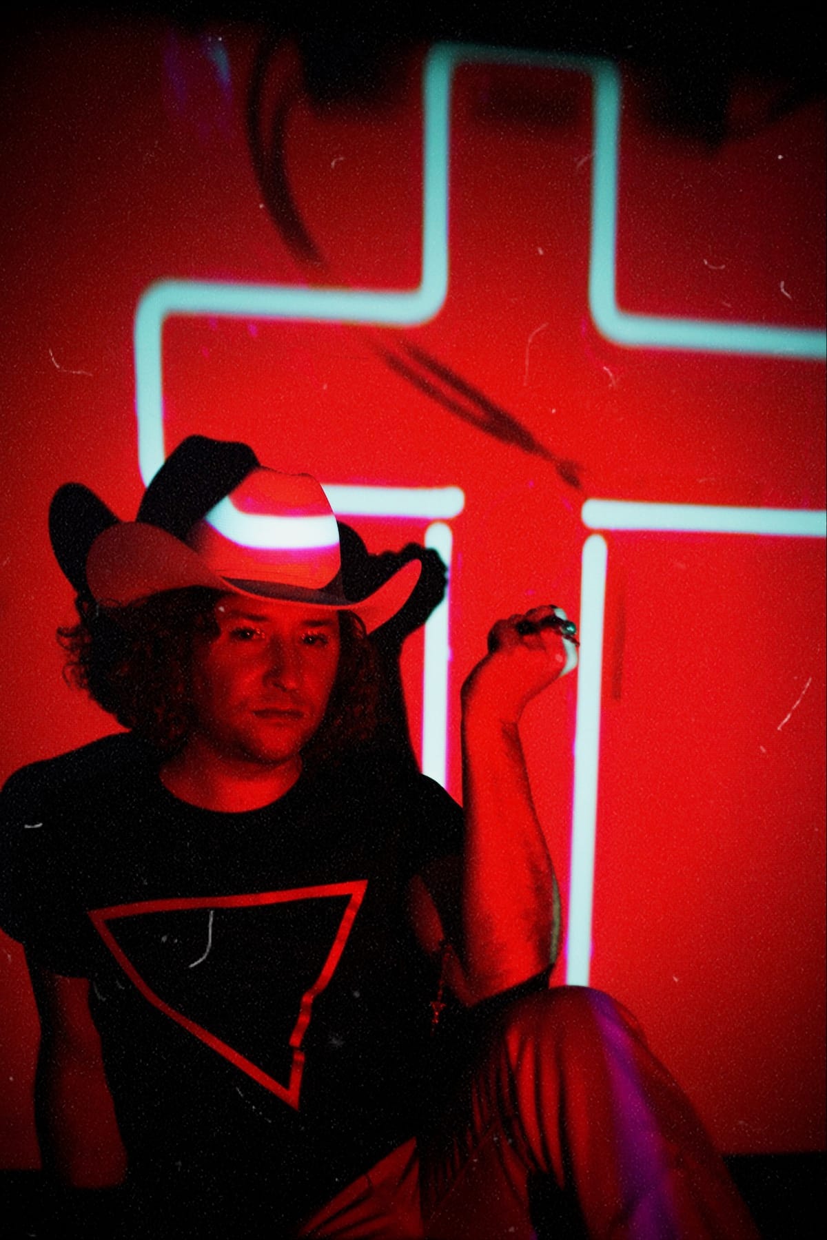 Paisley Fields in red neon light with a white cross in the background