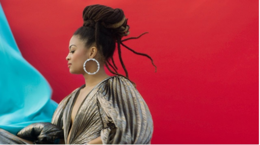 Valerie June in profile against a red background