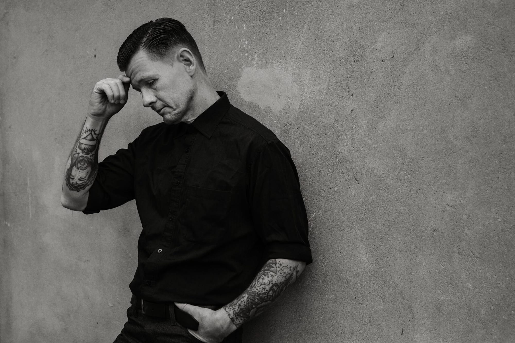 Black and white portrait of Jake La Botz, with tattooed arms visible