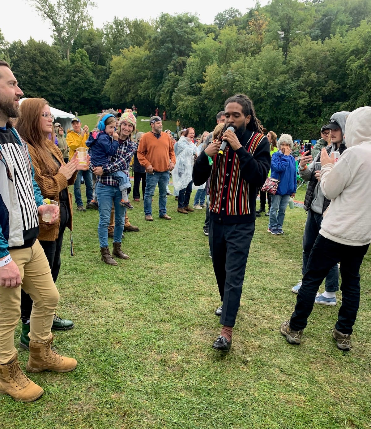 Thee Sacred Souls singer walks through the crowd on a grassy field.