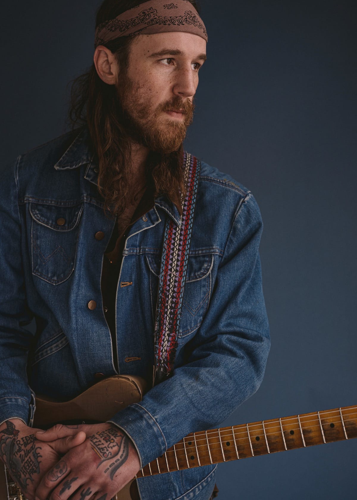 Alex Williams in denim jacket against blue backdrop
