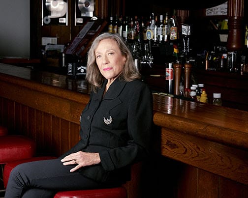 Angela Strehli sits in front of a wooden bar