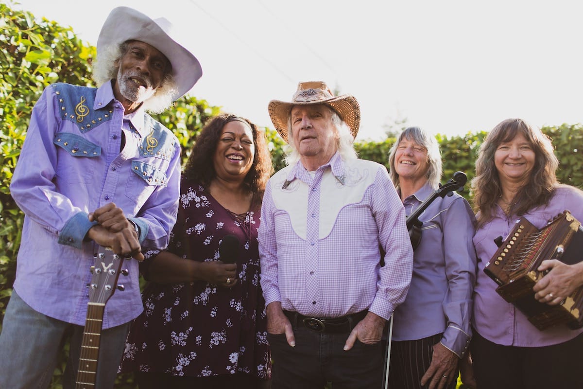 Five people, Patrick Haggerty at center, in lavender shirts as Lavender Country