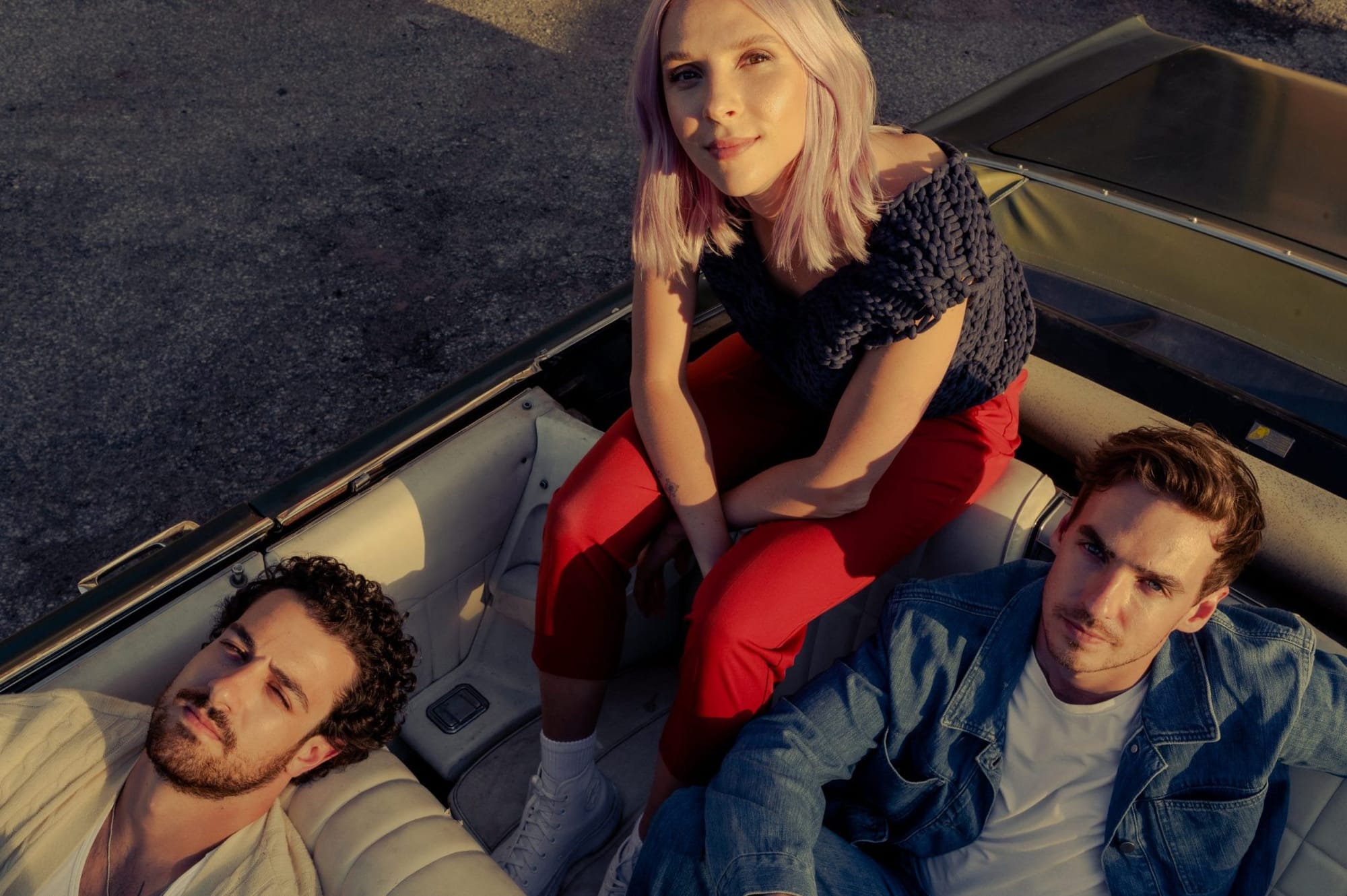 Wild Rivers trio sit in a convertible looking up at the camera