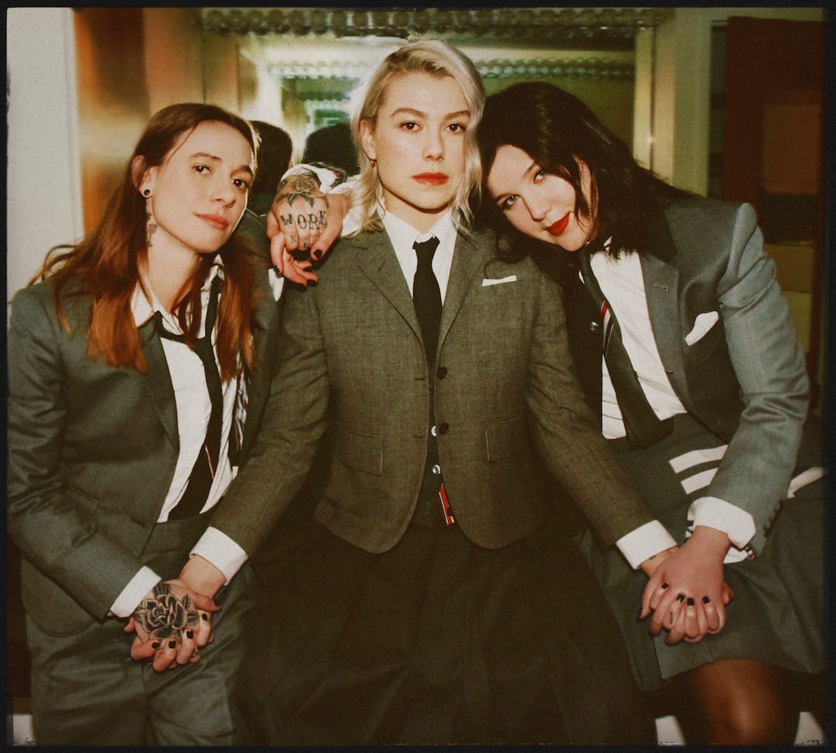 the three members of the boygenius trio in front of a dressing room mirror