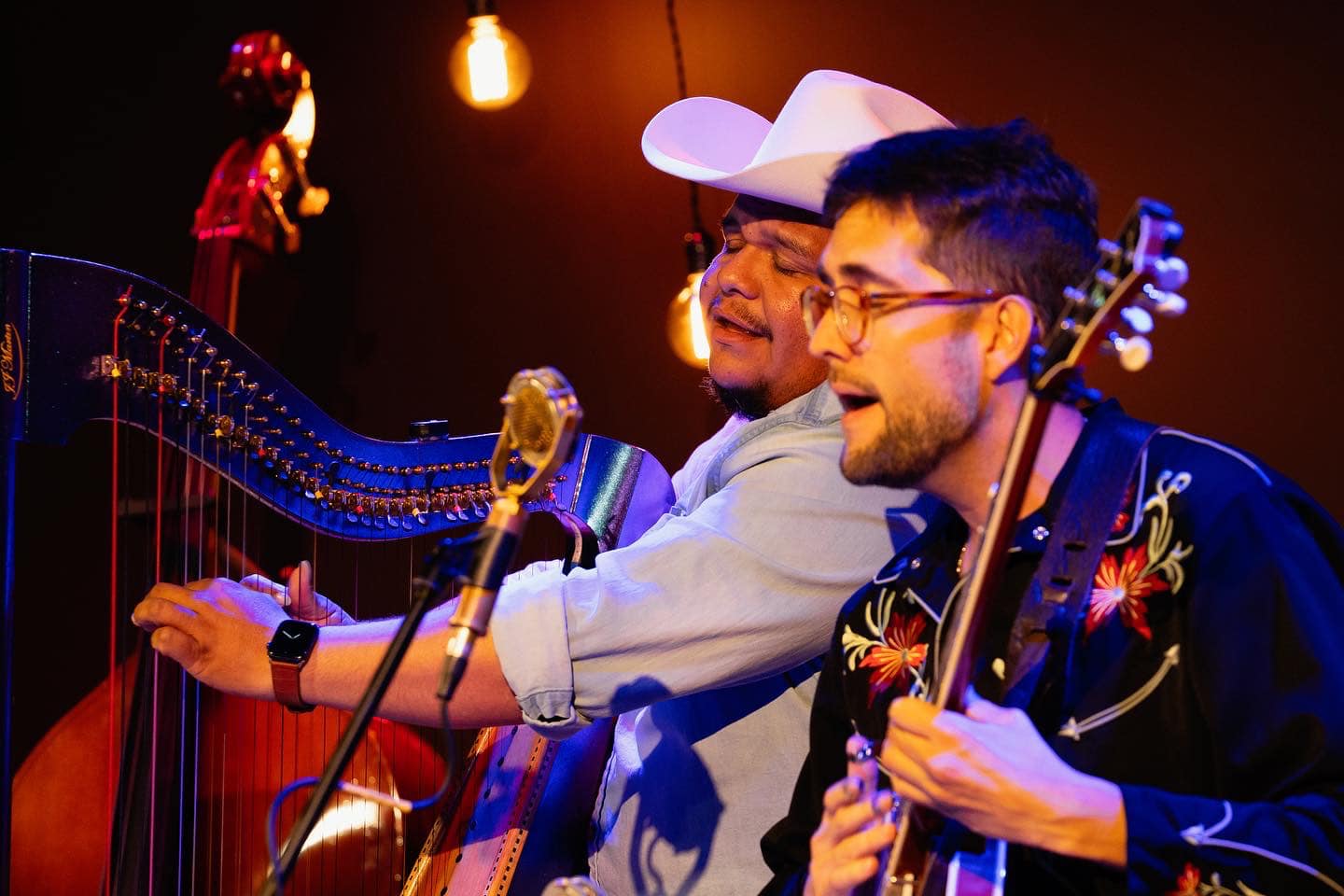 Larry Bellorin on harp and Joe Troop on banjo sing together during a performance.